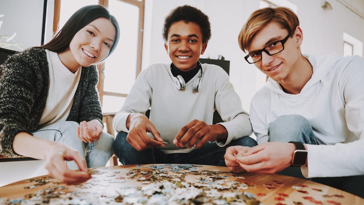 Parta řeší u stolu společně puzzle, podobně se hraje escape room
