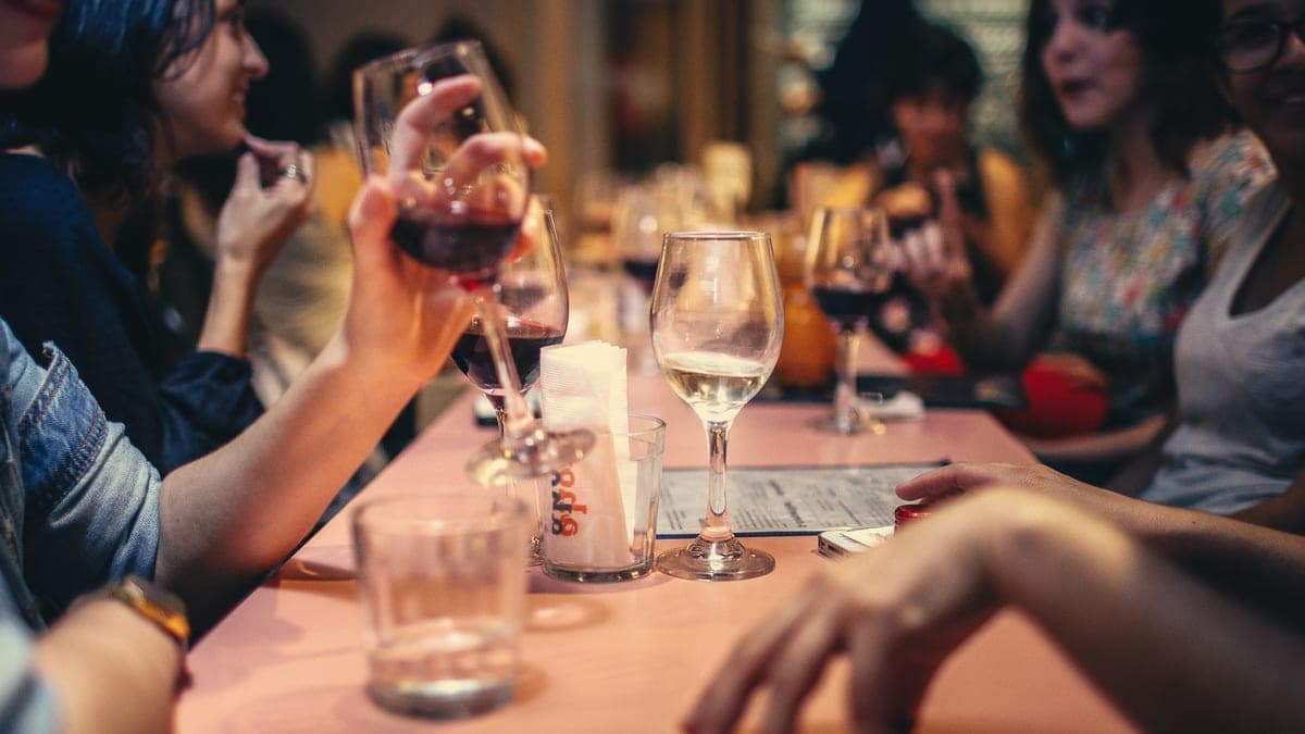 Spropitné za skupinu: parta u dlouhého stolu v restauraci si připíjí vínem